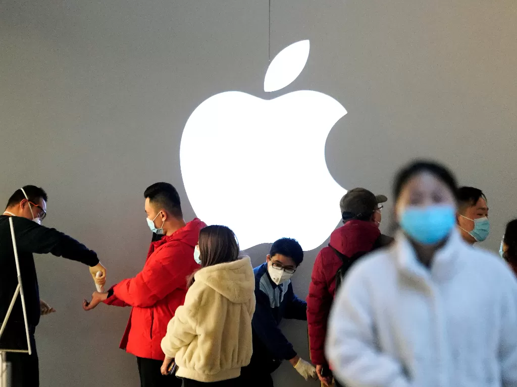 Pengunjung dengan masker menjalani pemeriksaan suhu tubuh di Apple Store di Shanghai, Tiongkok. (REUTERS/Aly Song)