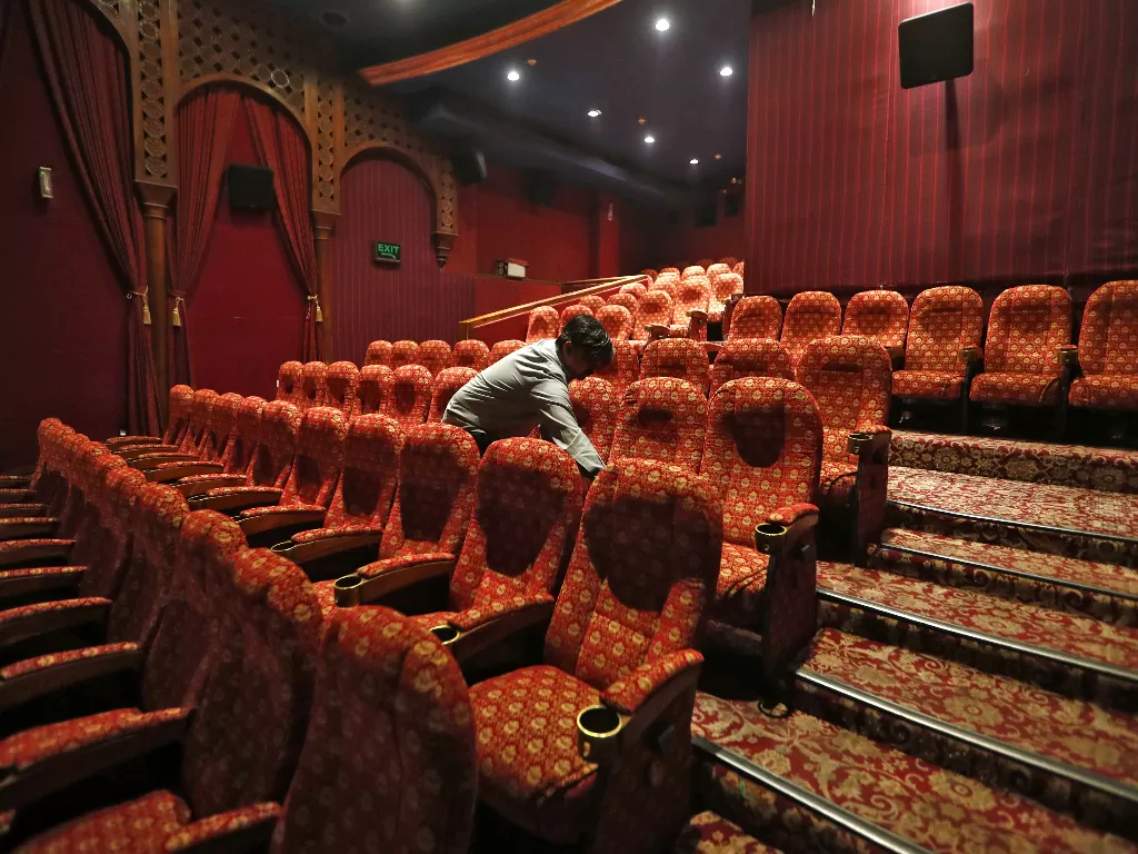 Seorang petugas membersihkan ruang teater di salah satu gedung bioskop di Delhi, India. (REUTERS/Adnan Abidi)