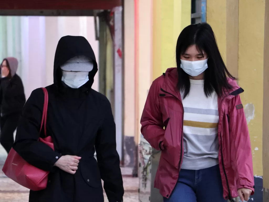 Ilustrasi dua orang wanita yang sedang berjalan menggunakan masker (Unsplash/Macau Photo Agency)