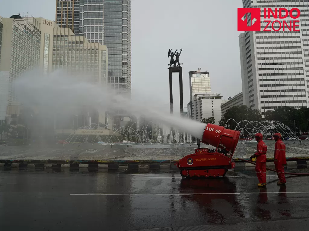 Petugas menyemprotkan cairan disinfektan di kawasan Bundaran HI, Jakarta, Minggu (22/3/2020). (INDOZONE/Arya Manggala)