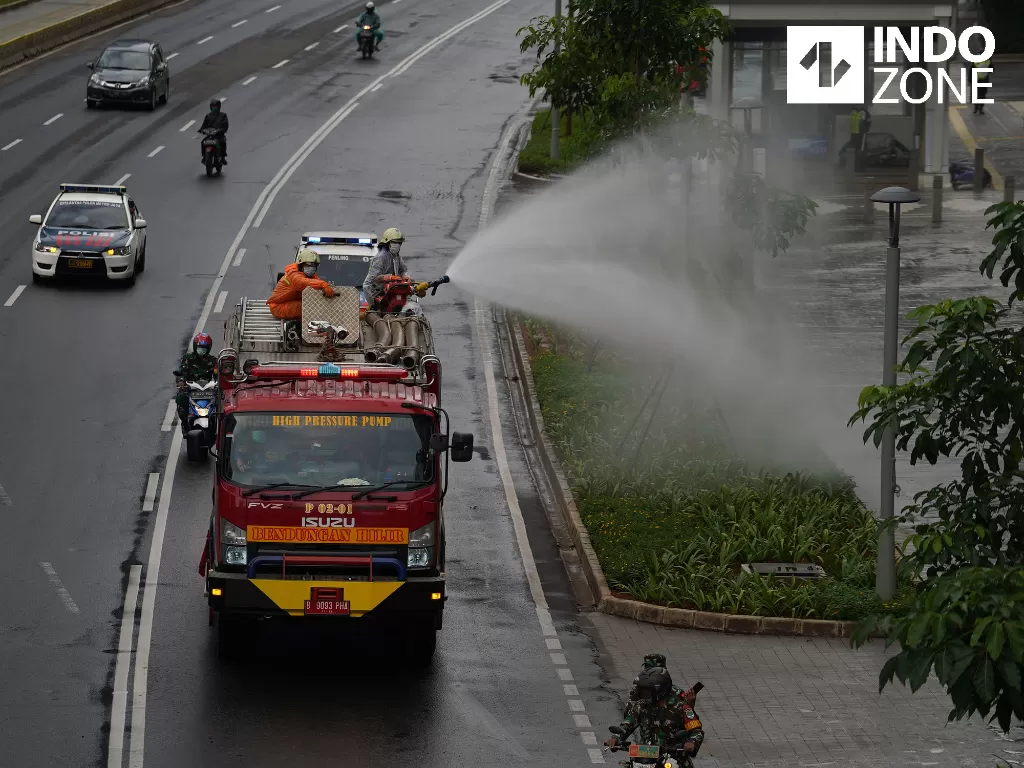 Petugas menyemprotkan cairan disinfektan di kawasan Jalan Sudirman, Jakarta, Minggu (22/3/2020). (INDOZONE/Arya Manggala)