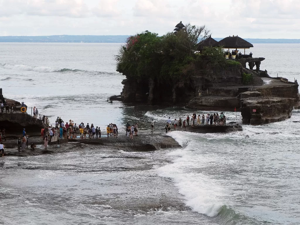 Wisatawan beraktivitas di Pantai Tanah Lot, Tabanan, Bali, Minggu (16/2). (ANTARA FOTO/Nyoman Hendra Wibowo)