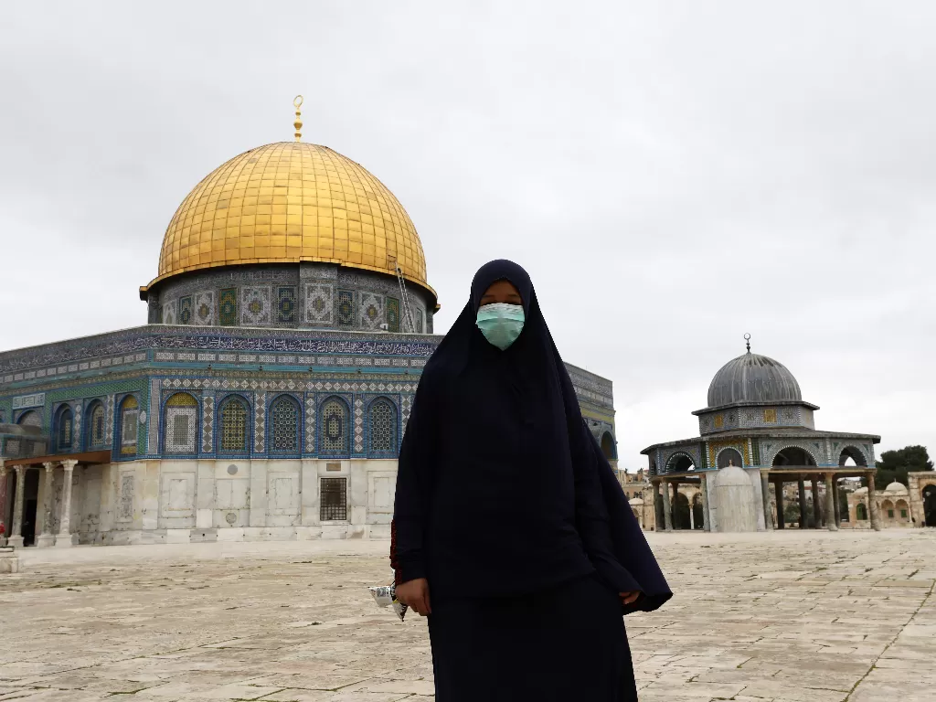 Seorang wanita memakai masker saat berada di sekitar masjid al aqsa. (REUTERS/Ammar Awad)