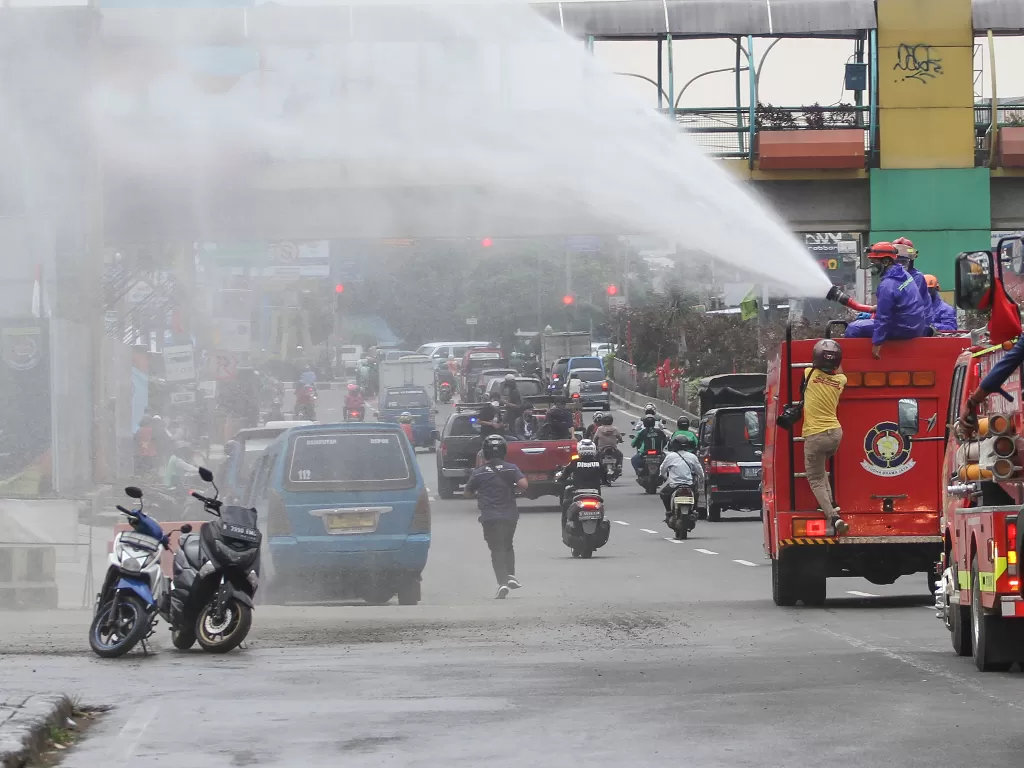 Petugas damkar semprotkan cairan disinfektan ke jalanan. (ANTARA FOTO/Asprilla Dwi Adha)