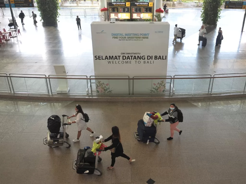 Penumpang pesawat membawa barang bawaannya di Terminal Kedatangan Internasional Bandara Internasional I Gusti Ngurah Rai Bali, Jumat (20/3). (ANTARA FOTO/Fikri Yusuf)