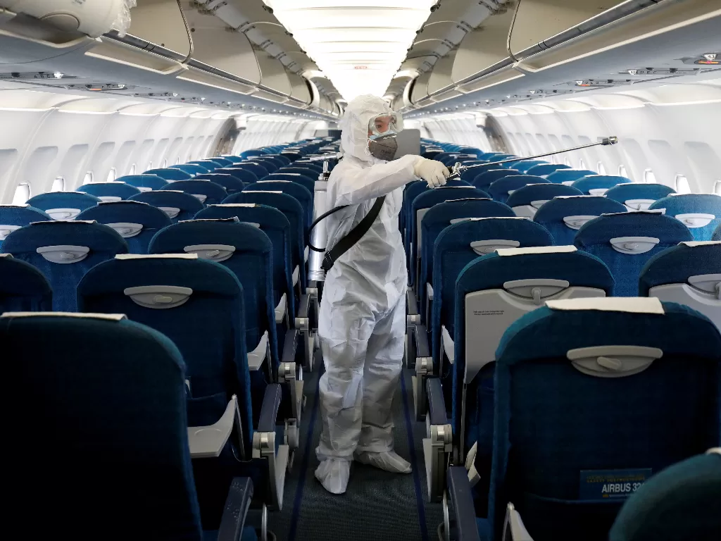 Seorang petugas kesehatan menyemprotkan disinfektan di dalam pesawat Vietnam Airlines. (REUTERS/Kham)