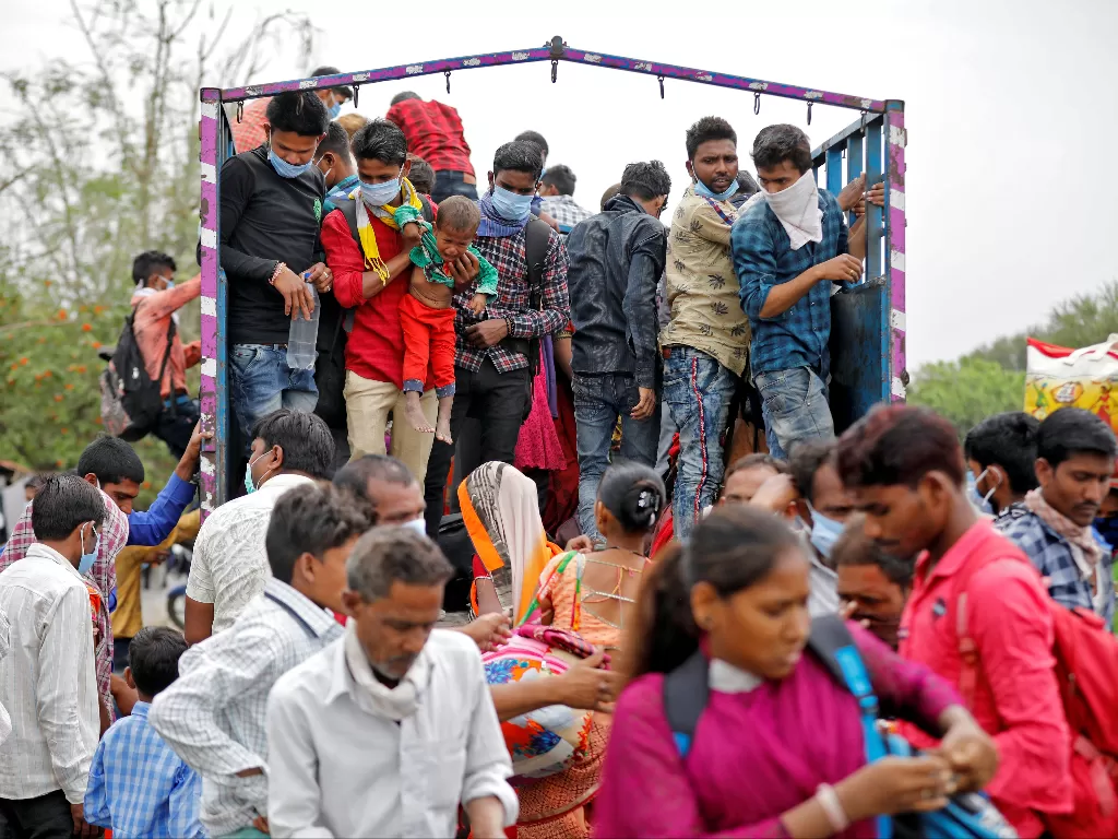 Pekerja migran dan keluarga mereka naik truk untuk kembali ke desa mereka setelah India memerintahkan lockdown selama 21 hari untuk membatasi penyebaran penyakit virus corona di Ahmedabad. (photo/REUTERS/Amit Dave)