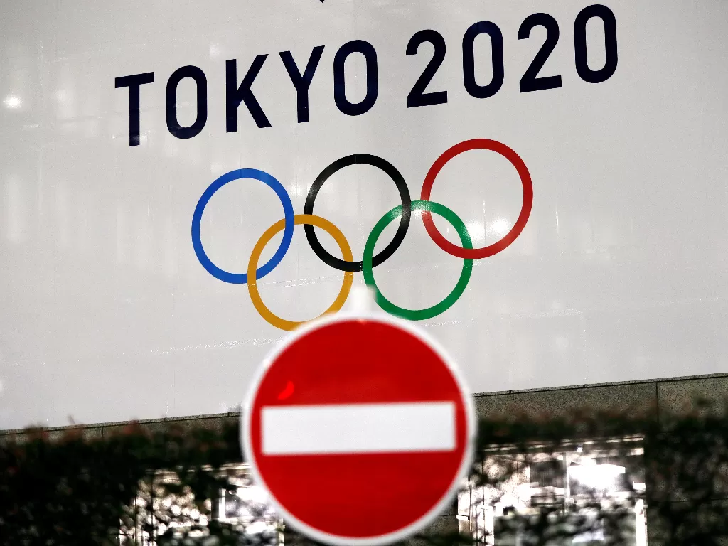 Sebuah spanduk untuk Olimpiade Tokyo 2020 mendatang terlihat di belakang rambu lalu lintas di Tokyo, Jepang. (photo/REUTERS/Issei Kato)