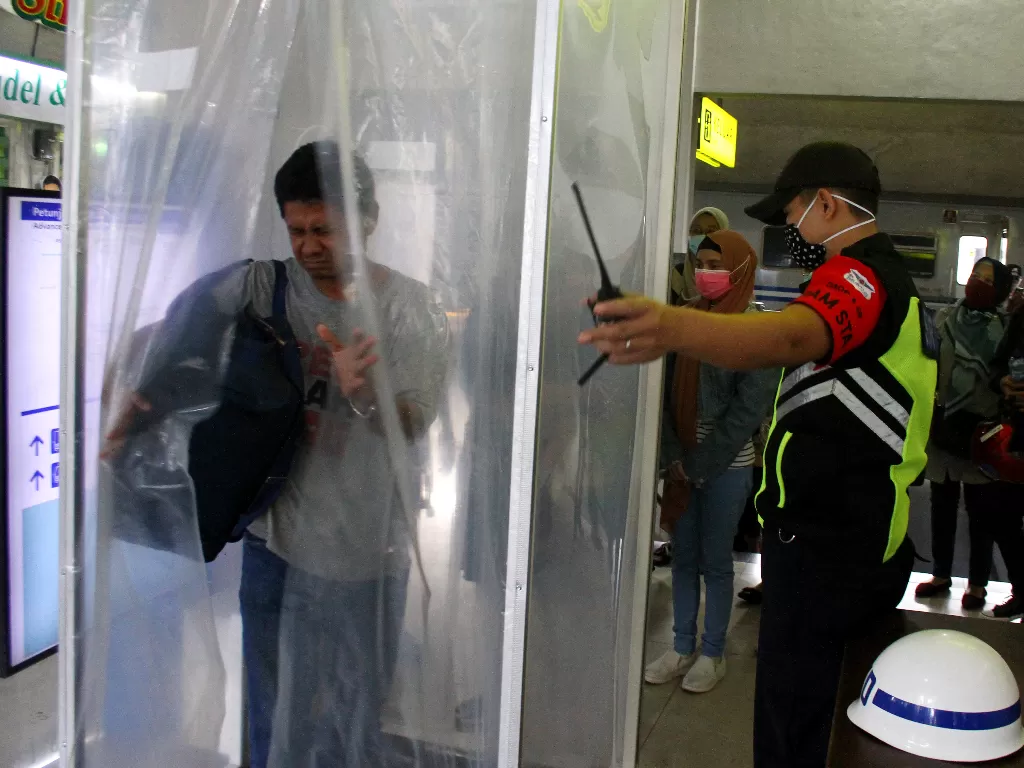 Potret warga saat henda keluar dari bilik disinfektan. (ANTARA FOTO/Ari Bowo Sucipto)