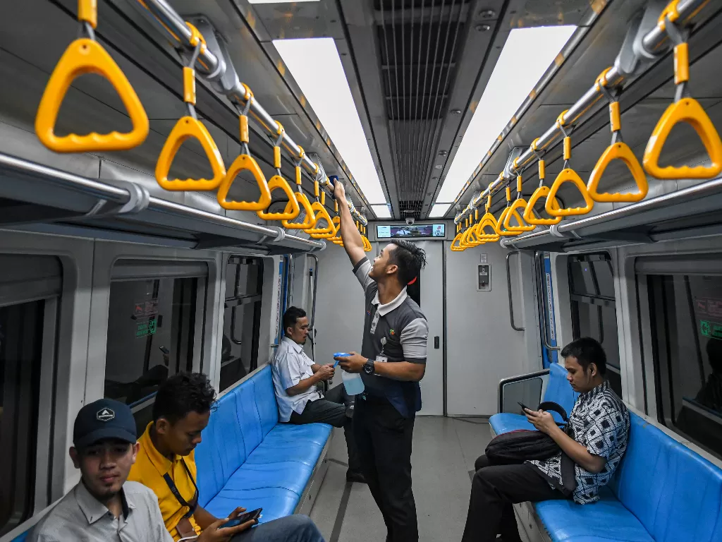 Petugas kebersihan membersihkan pegangan tangan (hand grip) gerbong LRT. Virus corona membuat penumpang LRT menurun drastis (ANTARA FOTO/Nova Wahyudi).