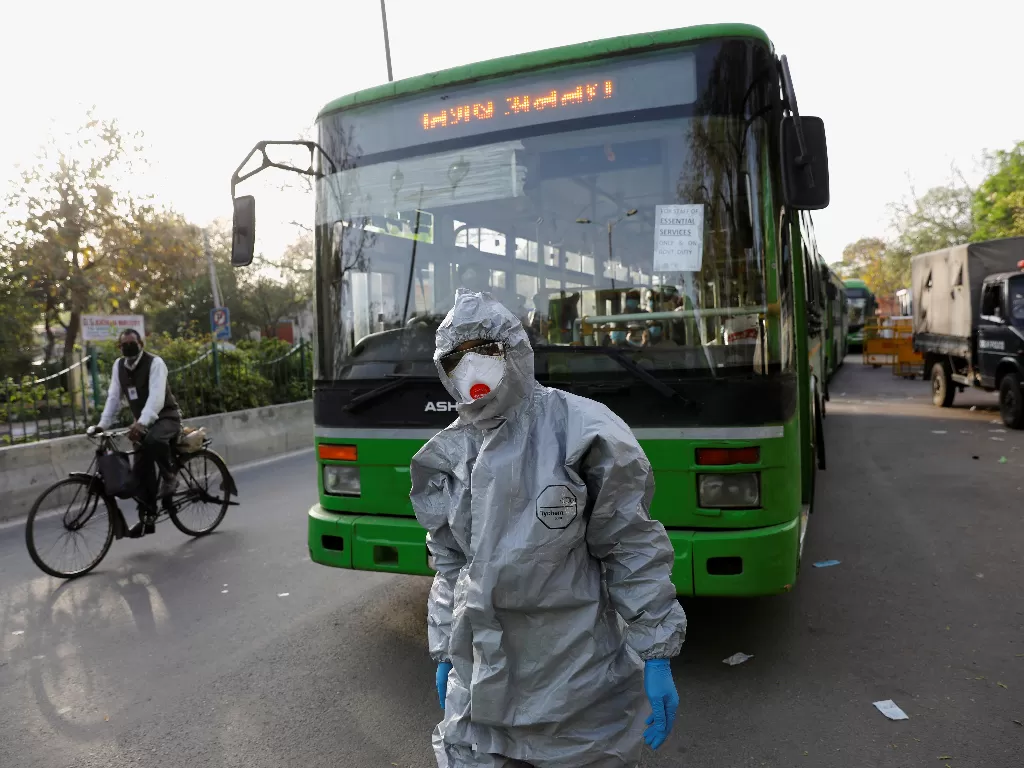 Ilustrasi. Seorang pengemudi yang mengenakan pakaian pelindung berjalan di depan sebuah bus yang membawa pembawa penyakit korona yang diduga ke fasilitas karantina, di tengah kekhawatiran tentang penyebaran penyakit Covid-19. (photo/REUTERS/Adnan Abidi)