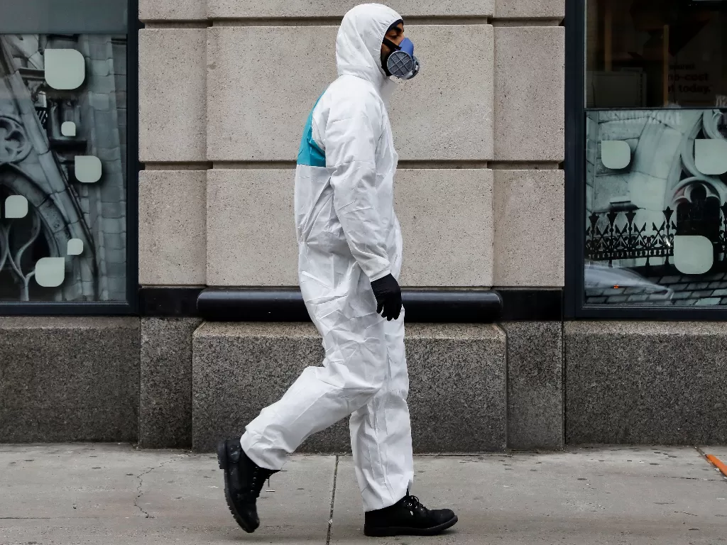 Seorang warga New York berjalan dengan alat perlindungan lengkap di First Avenue (REUTERS/Brendan McDermid)