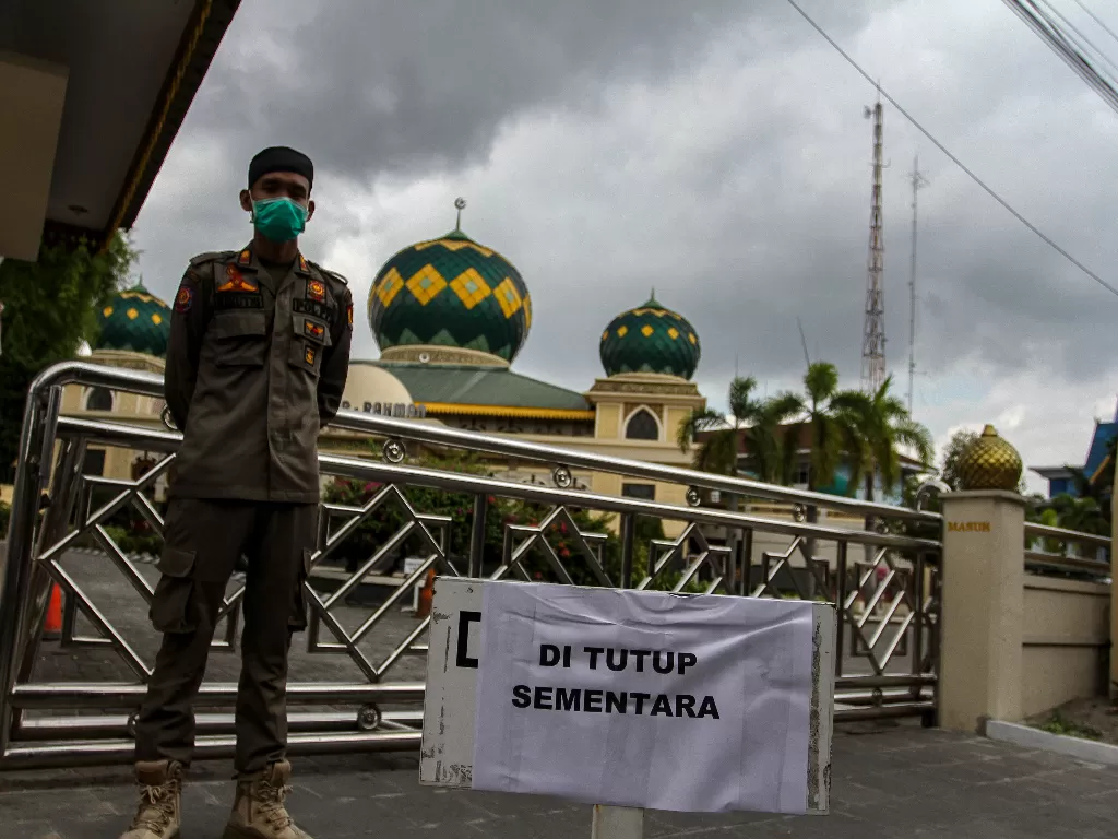 Petugas Satpol PP Kota Pekanbaru berjaga di depan pintu masuk Masjid Agung Ar-Rahman yang ditutup sementara, di Pekanbaru, Riau, Jumat (20/3/2020).  (ANTARA/Rony Muharrman)
