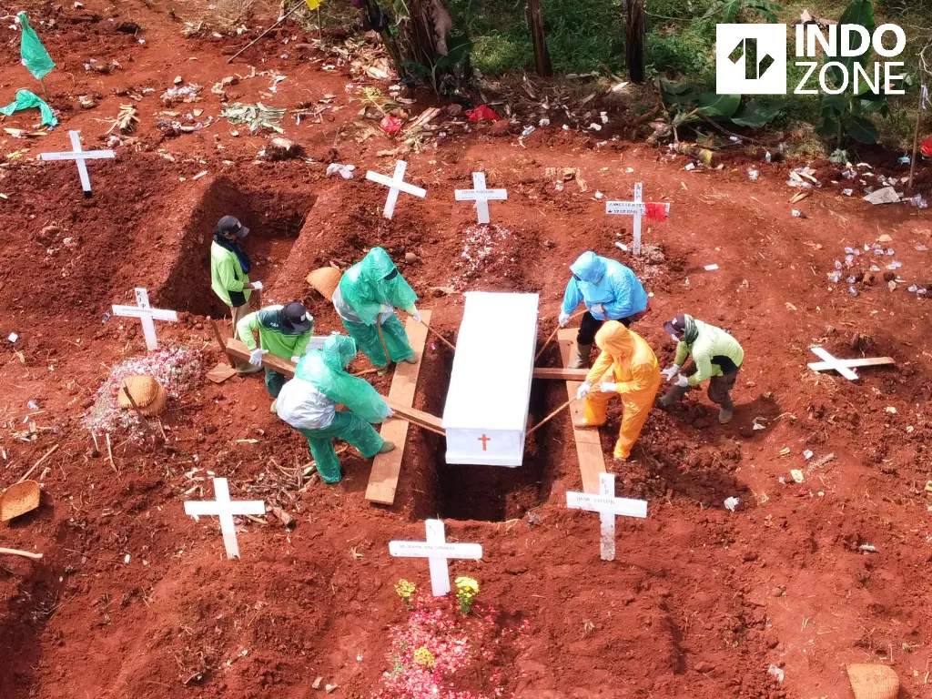 Petugas pemakaman menurunkan peti jenazah pasien Covid-19 di TPU Pondok Ranggon, Jakarta, Kamis (2/4/2020). (INDOZONE/Arya Manggala)