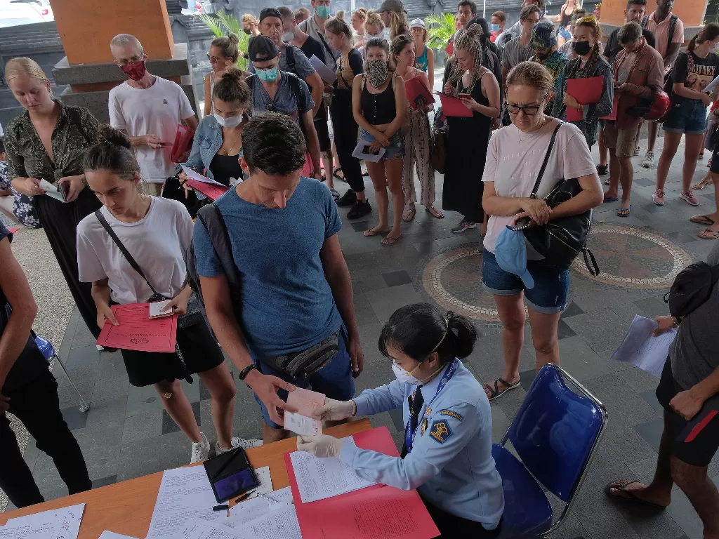Petugas imigrasi memeriksa dokumen warga negara asing (WNA) saat mereka antre mengurus perpanjangan visa dan permohonan izin tinggal di Bali. (ANTARA FOTO/Nyoman Hendra Wibowo)