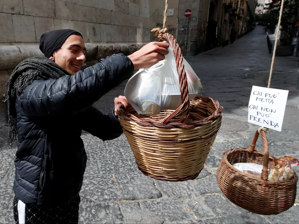 Seorang pria mengambil makanan dari keranjang di Italia. (photo/REUTERS/Ciro De Luca)