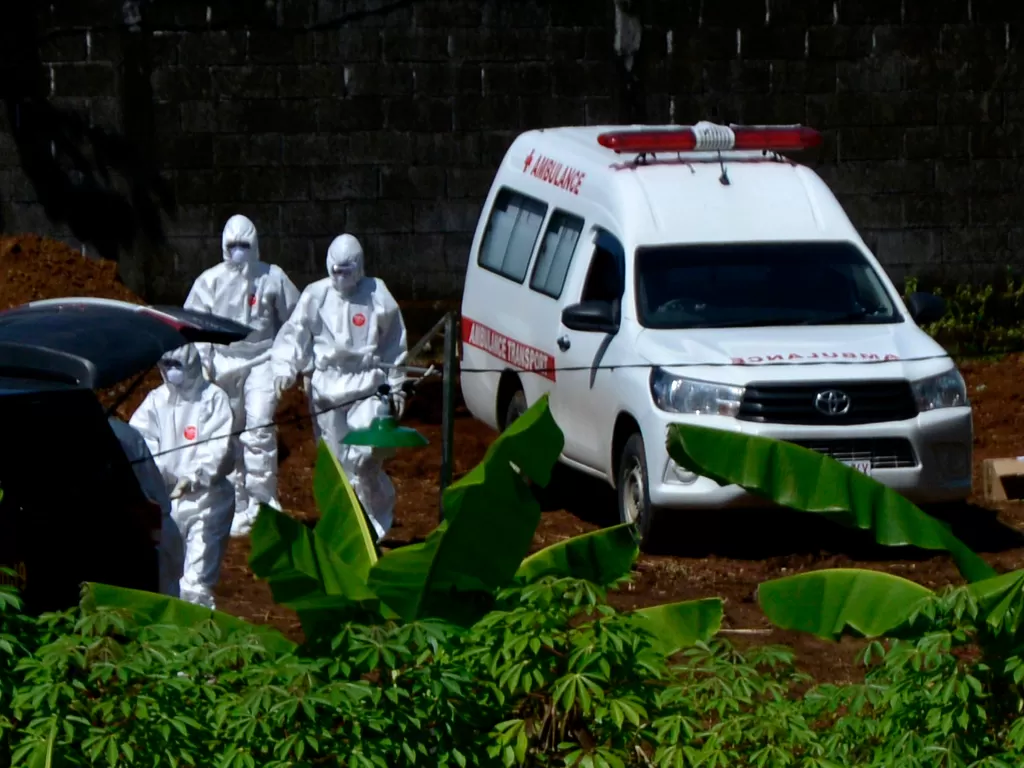 Petugas bersiap menurunkan jenazah pasien COVID-19 dari mobil ambulans saat akan dimakamkan, Minggu (5/4/2020). (ANTARA FOTO/Abriawan Abhe)