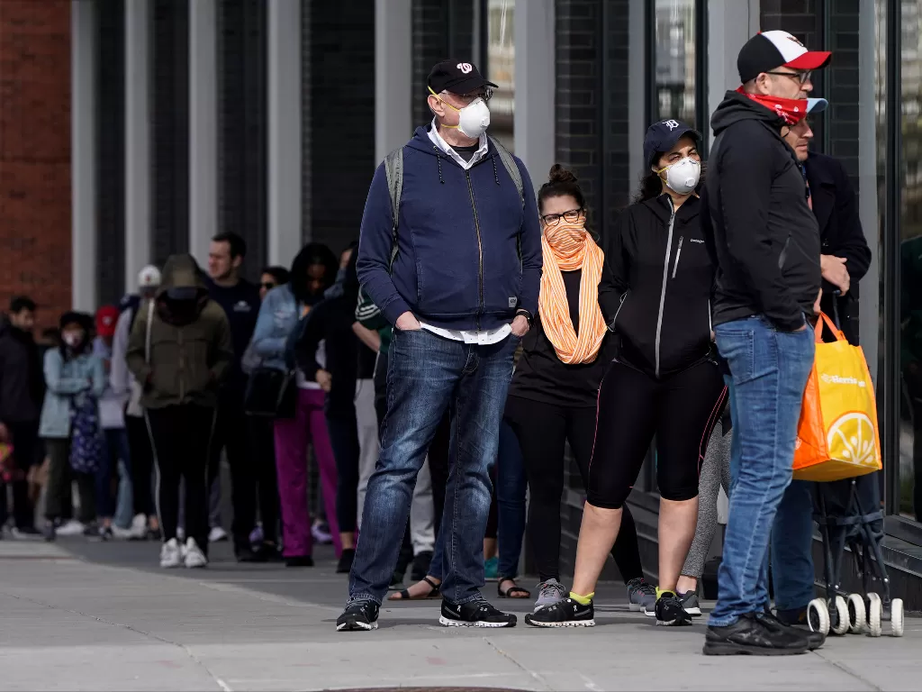 Orang-orang menutupi wajah mereka ketika mereka menunggu untuk memasuki toko di Washington. (photo/Reuters/Joshua Roberts)