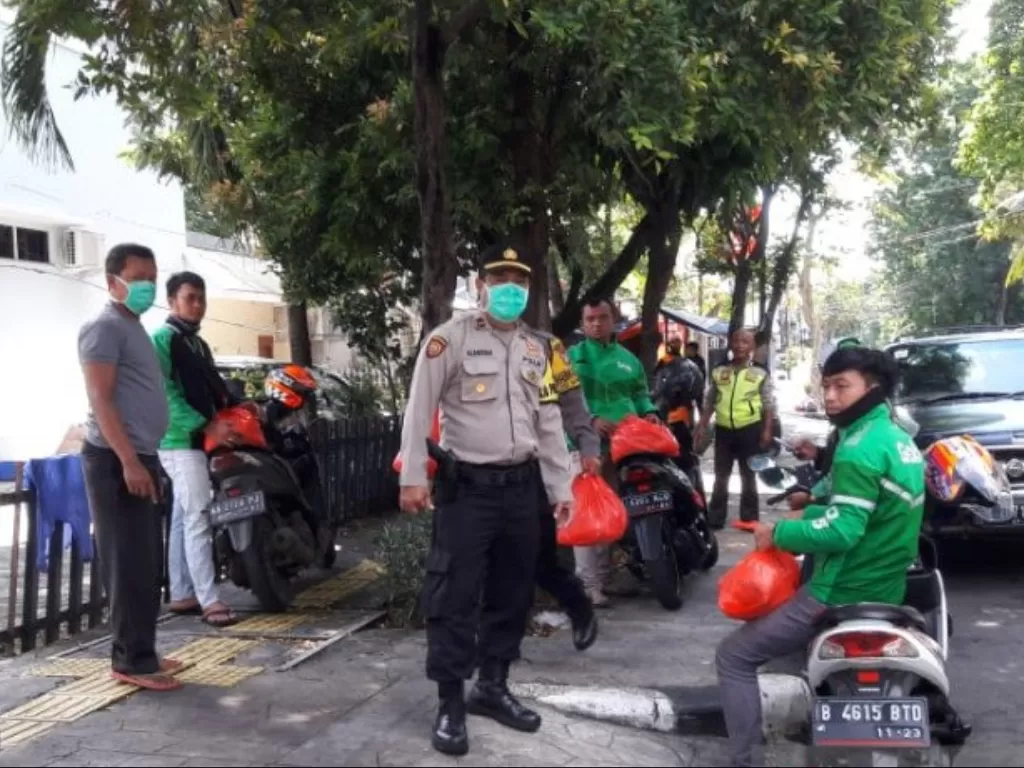 Anggota Polsek Tanjung Duren Jakarta Barat membagikan paket sembako kepada pengemudi ojek daring menjelang penerapan sosial berskala besar di Jakarta, Selasa (7/4/2020). (Photo/ANTARA/HO-Polres Metro Jakarta Barat)