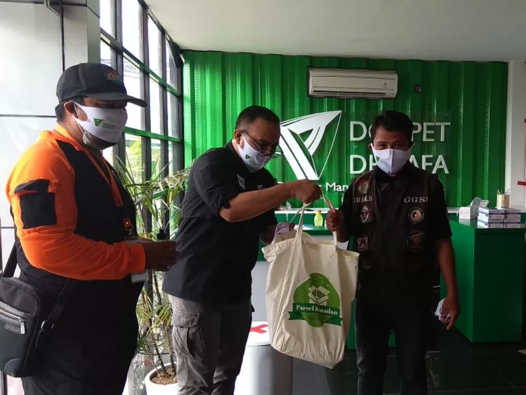 Direktur Eksekutif Dompet Dhuafa Imam Rulyawan menyerahkan bantuan masker dan hand sanitizer kepada perwakilan Ojol Nusantara. (Dok. Dompet Dhuafa)