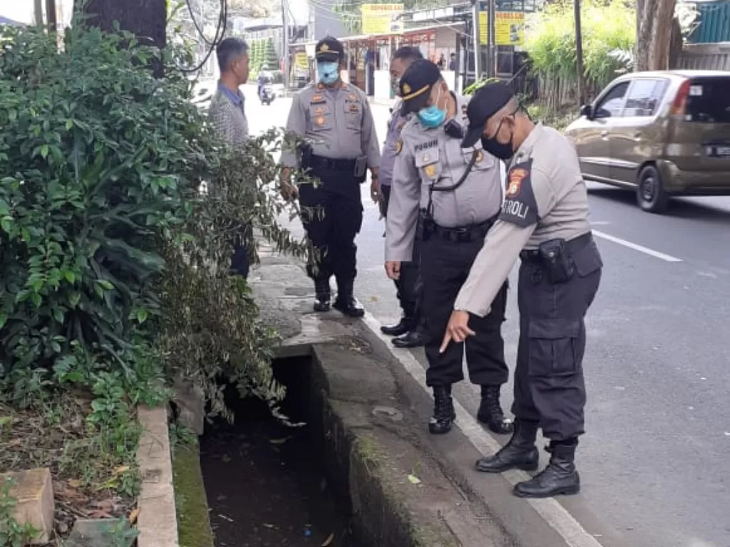 Polisi mengecek lokasi APD yang dibuang ke selokan Jagakarsa. (Humas Polda Metro Jaya)