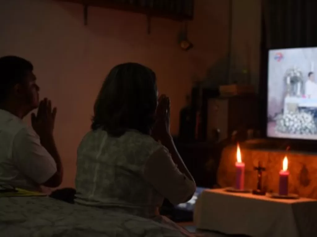 Umat Katolik mengikuti Misa Kamis Putih melalui media daring di rumahnya di Surabaya, Jawa Timur, Kamis (9/4/2020). Umat Katolik melaksanakan Misa Kamis Putih di rumah dengan menggunakan media daring guna mencegah penyebaran Virus Corona (COVID-19). Kamis