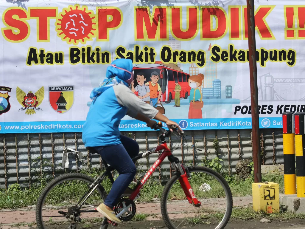 Warga melintas di depan spanduk bertuliskan 'stop mudik' di Kota Kediri, Jawa Timur, Rabu (8/4/2020). (ANTARA FOTO/Prasetia Fauzani)