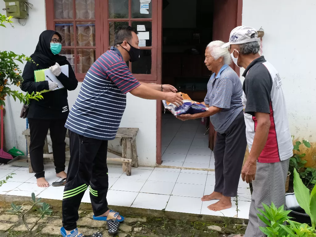 Petugas Jaring Pengaman Sosial (JPS) swadaya tingkat desa memberikan bantuan sembako kepada warga terdampak virus corona di Perumahan Candi Asri, Kedu, Temanggung, Jawa Tengah. (ANTARA FOTO/Anis Efizudin)