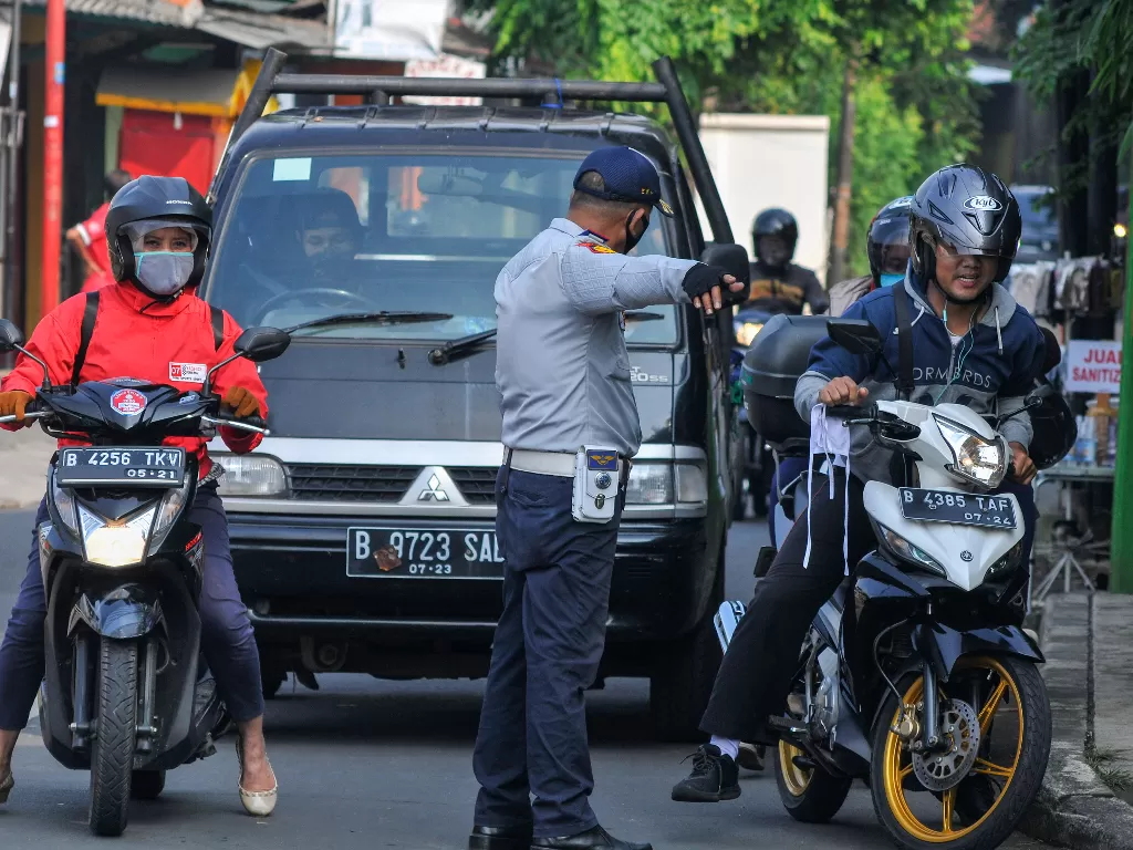 Petugas Dishub memberhentikan pengendara motor yang tidak memakai masker di Perbatasan Bekasi menuju Jakarta di Pondok Gede, Bekasi, Jawa Barat. (ANTARA/Fakhri Hermansyah)