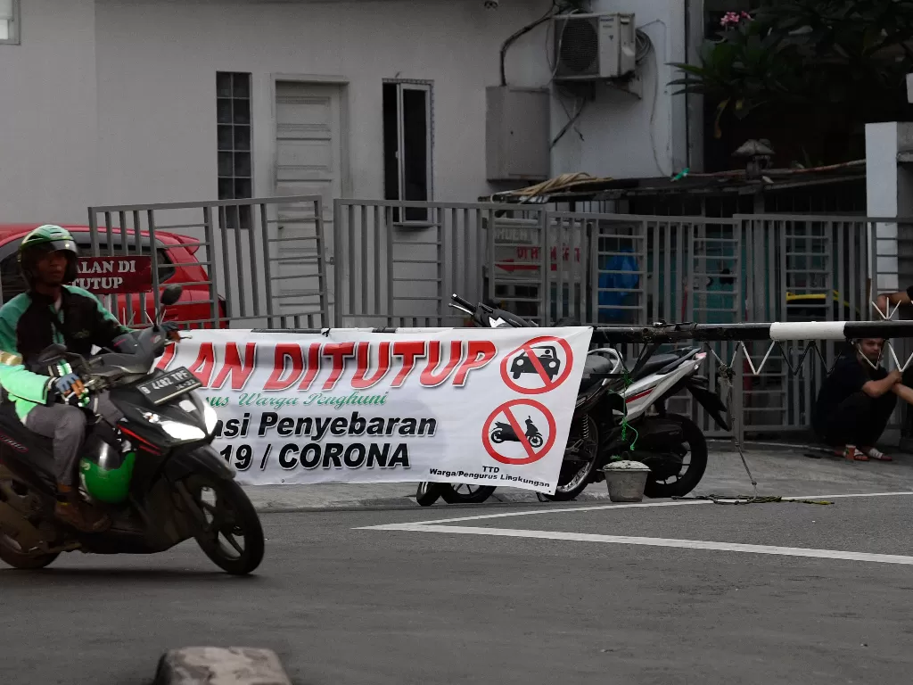 Pengemudi ojek online melintasi spanduk penutupan jalan di kawasan Pondok Pinang, Jakarta, Rabu (1/4/2020).(ANTARA/Puspa Perwitasari)