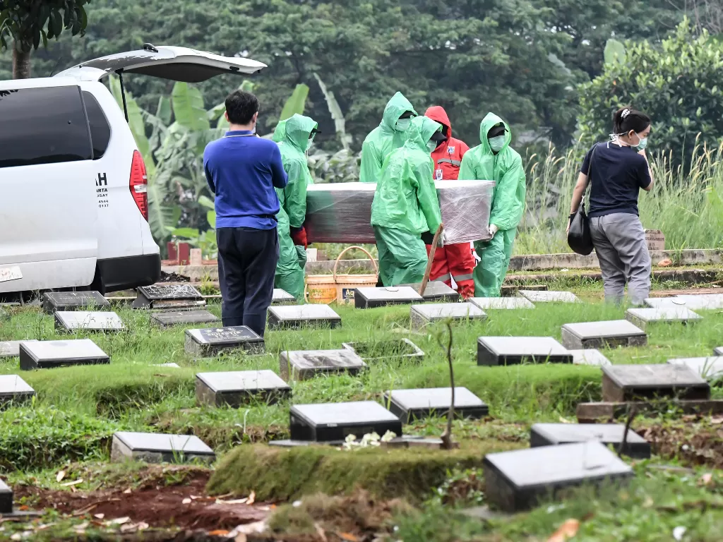 Petugas pemakaman membawa peti mati korban virus corona untuk dimakamkan. (ANTARA FOTO/Muhammad Adimaja)