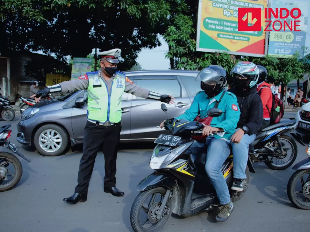 Petugas menghimbau pengguna kendaraan bermotor saat melakukan Pengawasan Pelaksanaan PSBB di Jalan Jatiwaringin, Bekasi, Jawa Barat, Rabu (15/4/2020). (INDOZONE/Febio Hernanto)