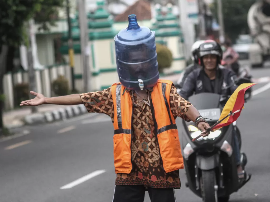 Sukarelawan Pengatur Lalu Lintas (Supeltas) mengatur lalu lintas mengenakan pelindung wajah dari galon air bekas di Jalan Tamansiswa, DI Yogyakarta, Rabu (15/4/2020). (ANTARA FOTO/Hendra Nurdiyansyah)