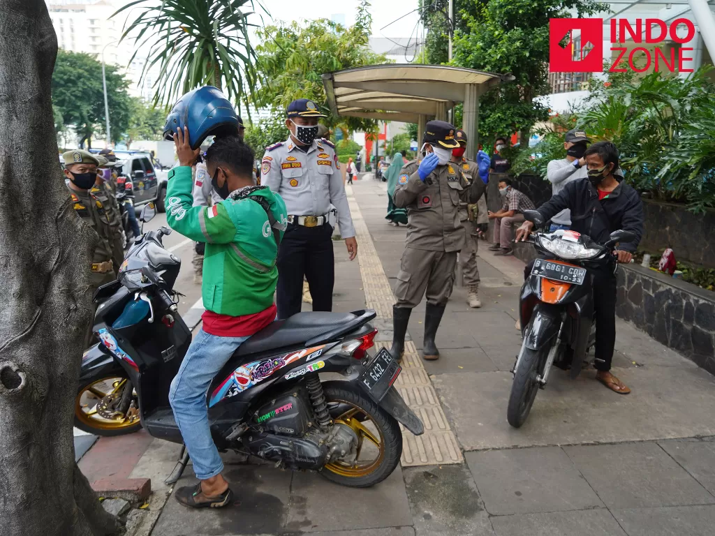 Petugas gabungan Satpol PP, Polisi dan Dinas Perhubungan melakukan penertiban kerumunan warga di sepanjang Jalan Hayam Wuruk, Jakarta, Rabu (15/4/2020). (INDOZONE/Arya Manggala)