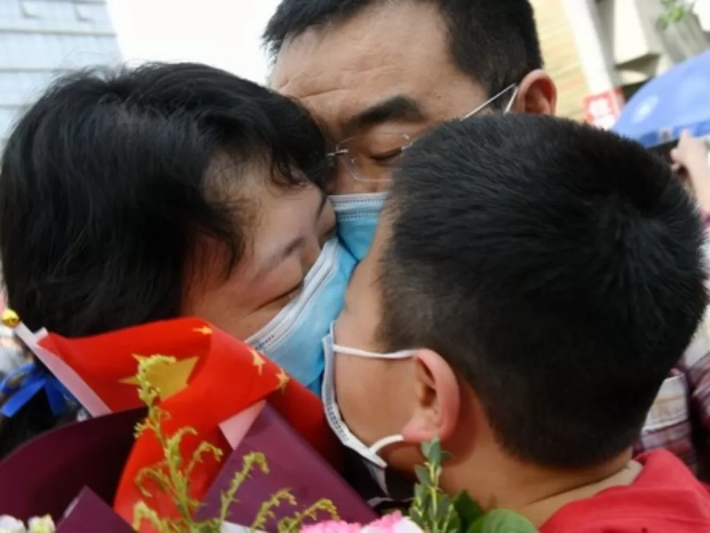 Long Junhong (kiri), anggota tim bantuan medis dari Rumah Sakit Afiliasi Kedua Universitas Xi'an Jiaotong, memeluk suami dan putranya di Xi'an, ibu kota Provinsi Shaanxi, Tiongkok barat laut, pada 15 April 2020. (Xinhua/Li Yibo)