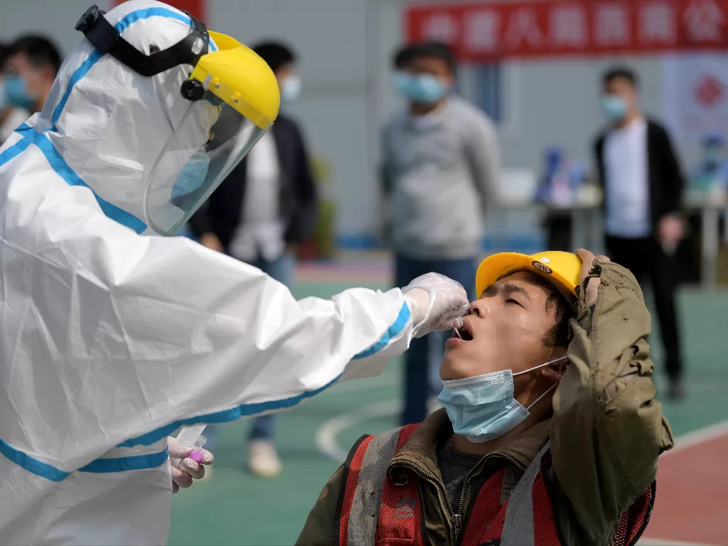 Seorang pekerja dalam pakaian pelindung mengumpulkan kapas dari pekerja konstruksi untuk uji asam nukleat di Wuhan, provinsi Hubei. (Photo/REUTERS/China Daily)