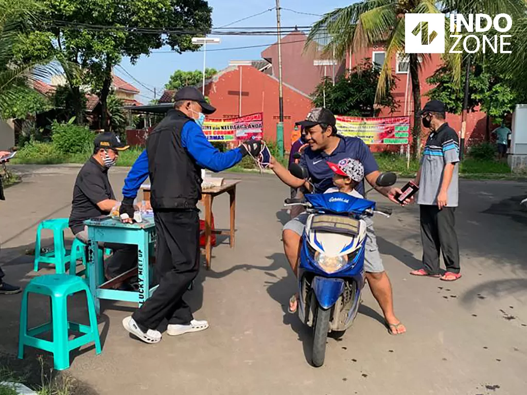 Pengurus RW 22 Perumahan Alam Asri 1 Vila Dago Pamulang memberikan masker kepada warga yang hendak keluar rumah di hari pertama pelaksanaan PSBB Kota Tangsel, Sabtu (18/4/2020). (INDOZONE/Tjahyo Utomo)