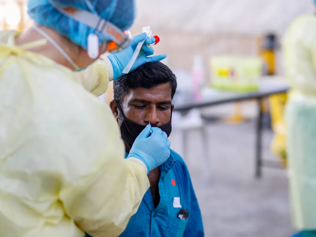Staf medis melakukan pemeriksaan terhadap seorang pria guna mendeteksi paparan virus corona. (REUTERS/MINISTRY OF MANPOWER, SINGAPORE)