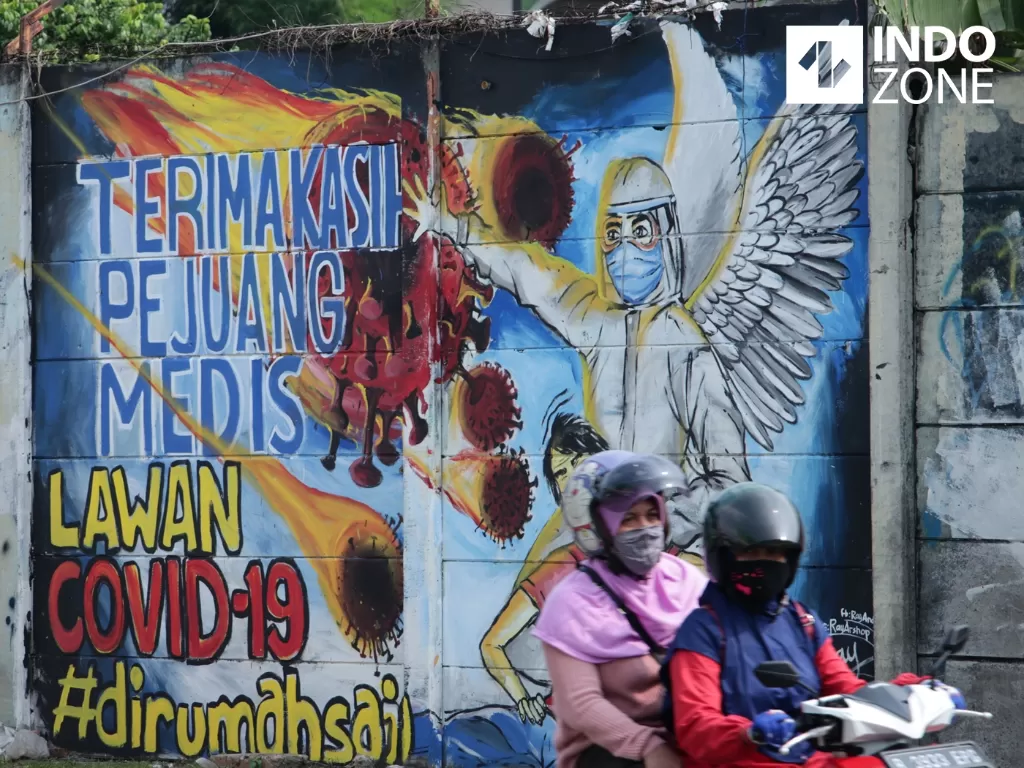 Warga melintasi mural edukasi terkait virus corona di Depok, Jawa Barat, Senin (20/4/2020). (INDOZONE/Febio Hernanto)