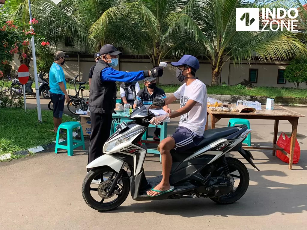 Petugas RW 22 Perumahan Alam Asri 1 Vila Dago Pamulang memeriksa suhu tubuh warga di Tangerang Selatan, Sabtu (18/4/2020). (INDOZONE/Tjahyo Utomo)