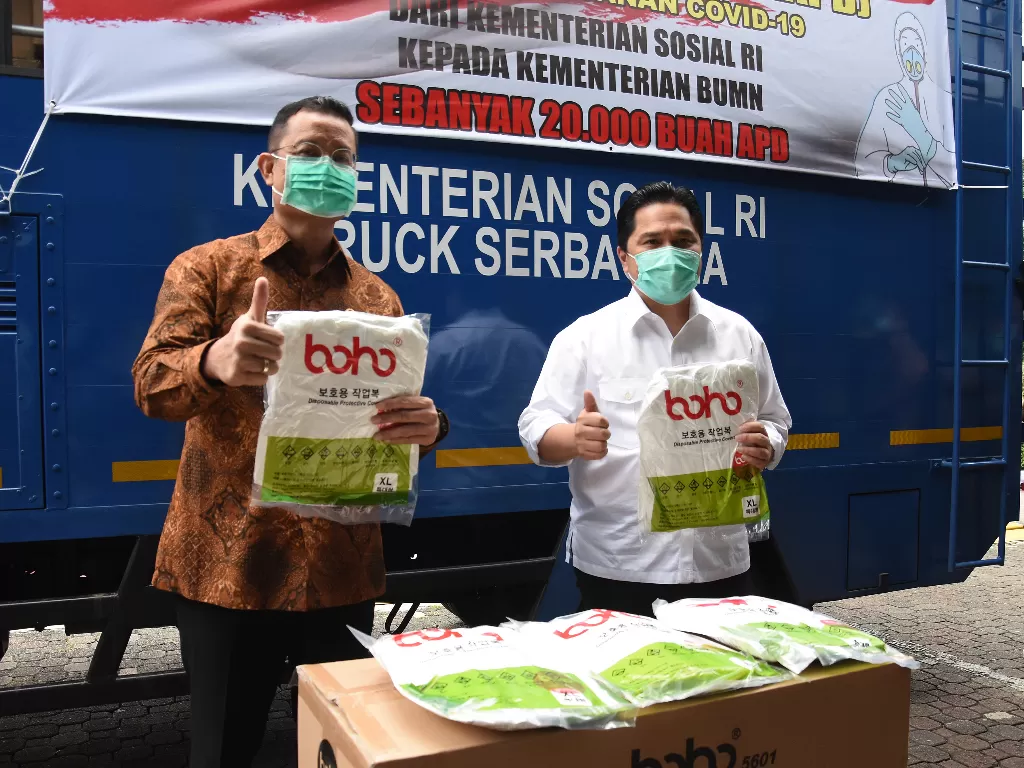 Menteri Sosial Juliari Batubara (kiri) menyerahkan bantuan alat pelindung diri (APD) untuk tenaga medis kepada Menteri BUMN Erick Thohir (kanan) di Gedung Kementerian BUMN, Jakarta, Selasa (7/4/2020). (ANTARA FOTO/Indrianto Eko Suwarso)