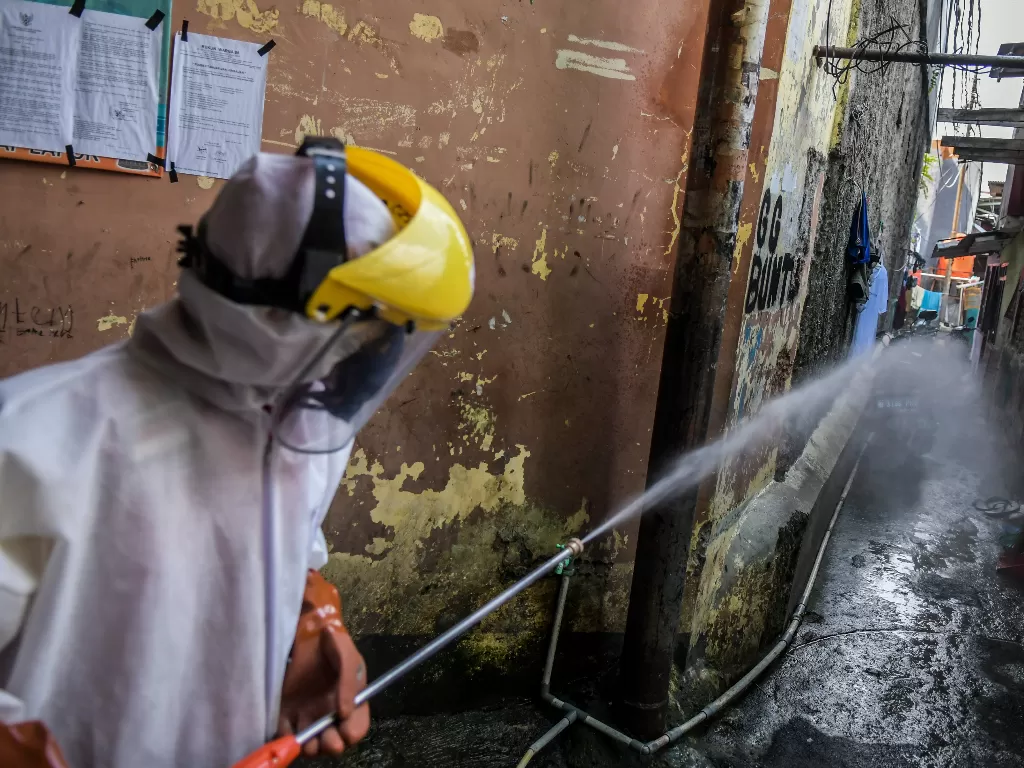 Petugas PMI menyemprotkan cairan disinfektan di rumah warga sekitar kawasan asrama Sekolah Tinggi Teologi Bethel, Jakarta (ANTARA FOTO/Galih Pradipta)