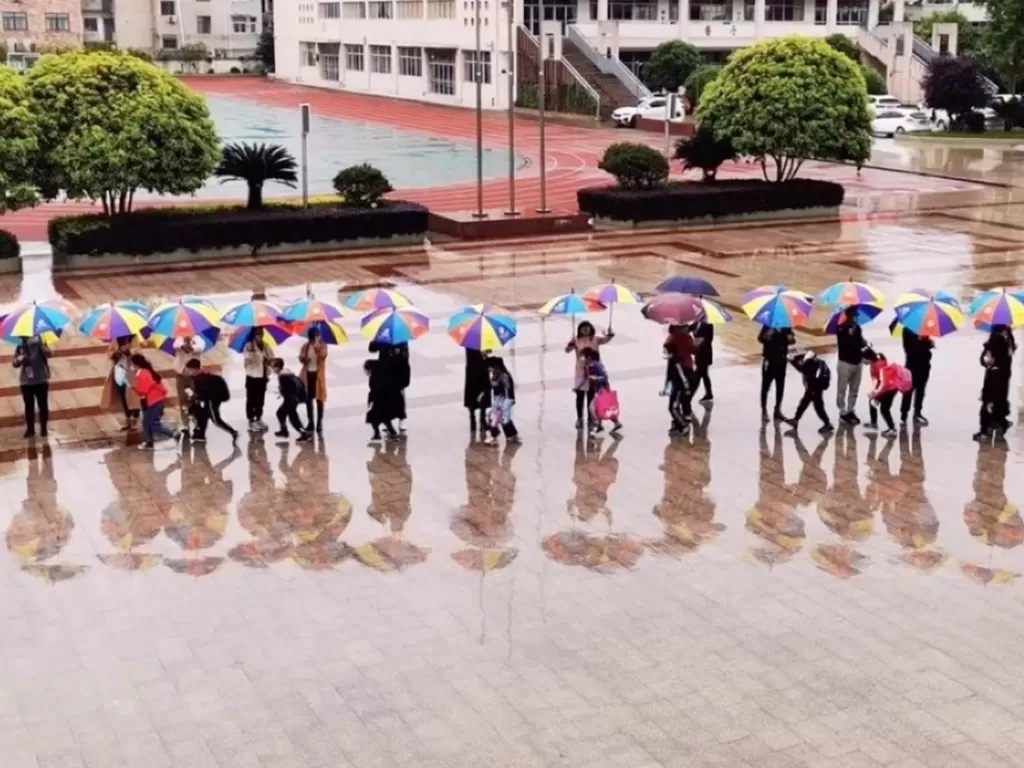 Para guru memayungi murid agar tidak kehujanan (SCMP)