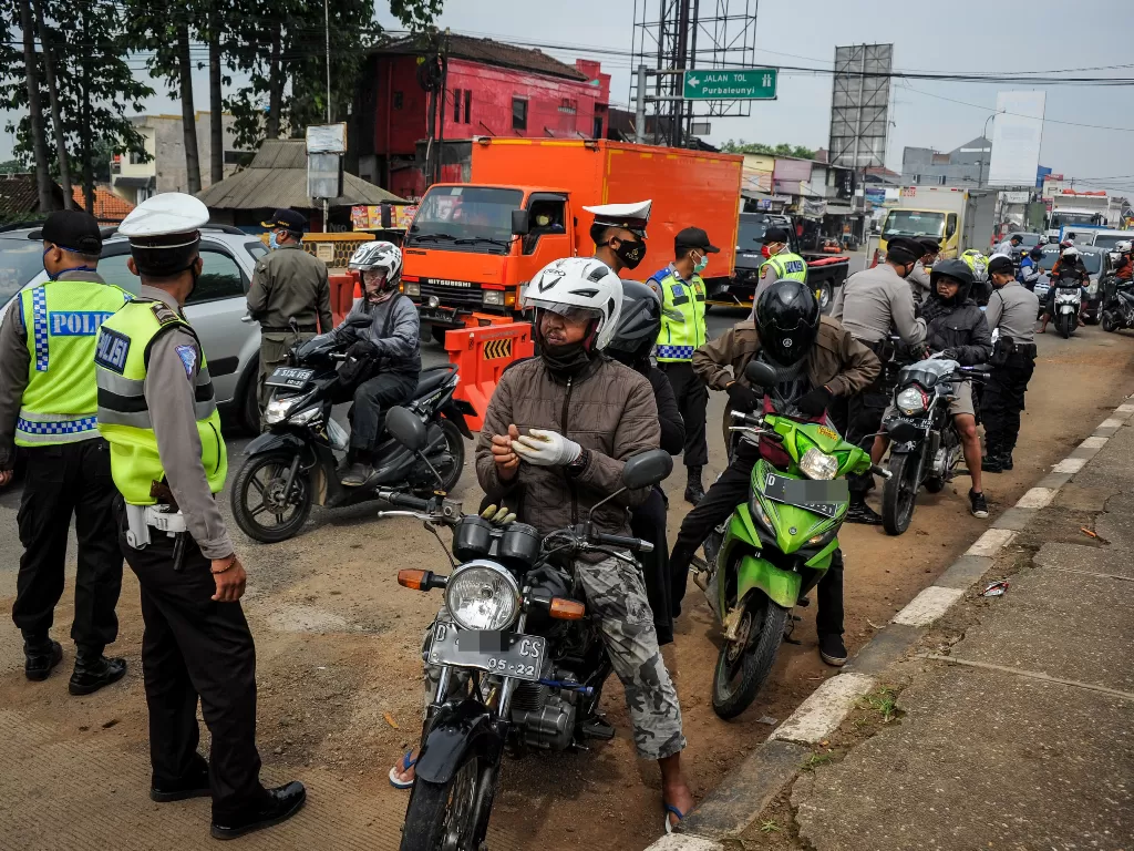 Petugas memberhentikan kendaraan bermotor di titik penyekatan larangan mudik di Jatinangor, perbatasan Kabupaten Bandung dan Kabupaten Sumedang, Jawa Barat, Sabtu (25/4/2020). (ANTARA/Raisan Al Farisi)