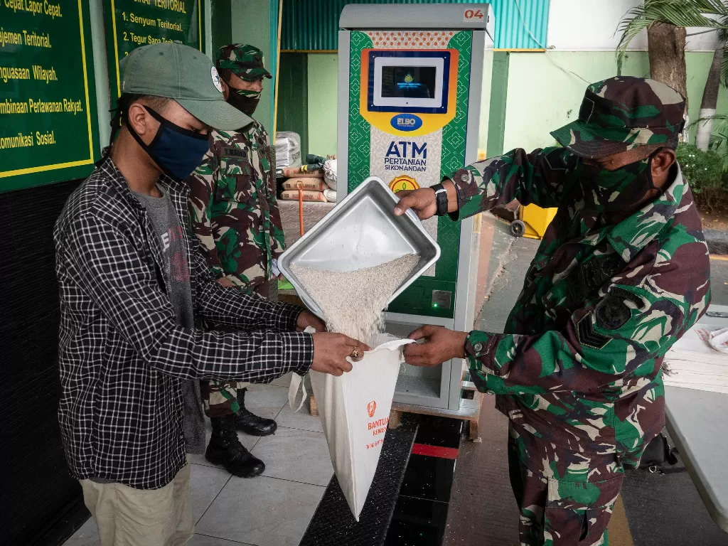 Prajurit TNI membantu warga mendapatkan beras gratis dengan ATM Pertanian Si Komandan di Kodim 0503/JB, Jakarta, Senin (27/4/2020). (ANTARA FOTO/Dhemas Reviyanto)