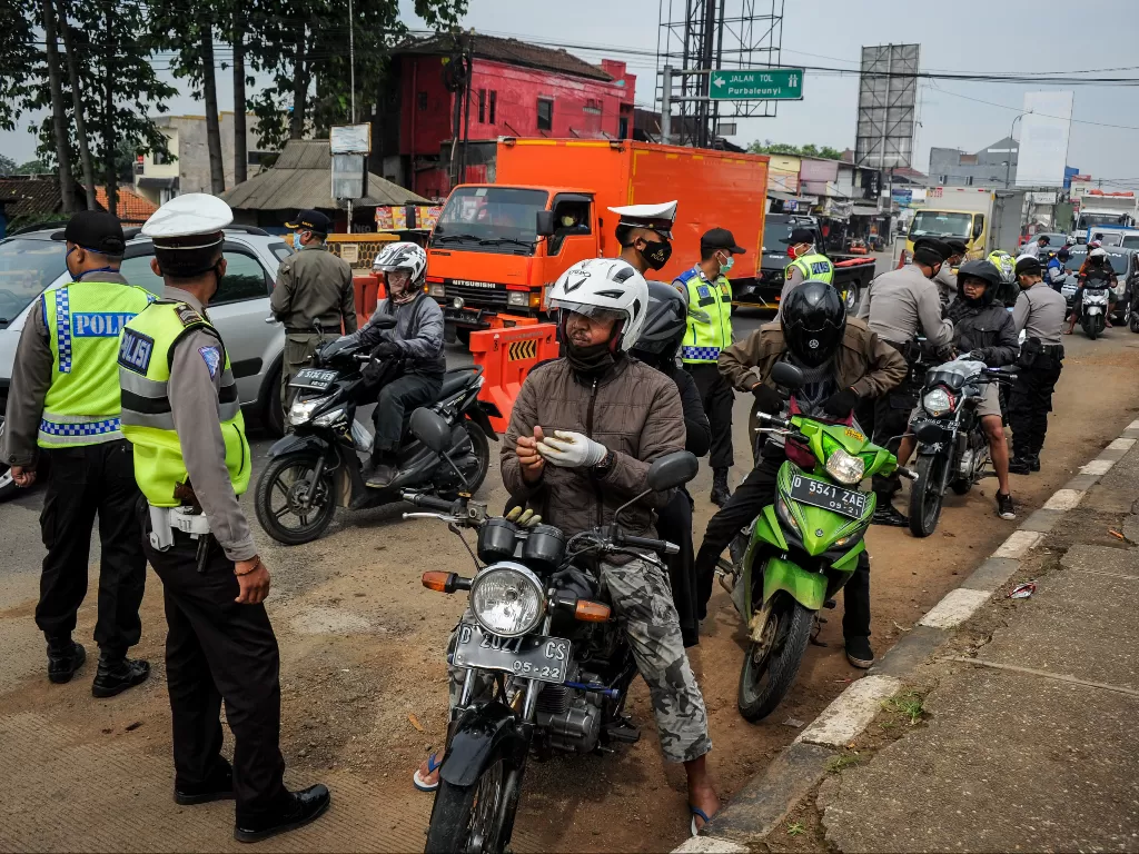Petugas memberhentikan kendaraan bermotor di titik penyekatan larangan mudik di Jatinangor, perbatasan Kabupaten Bandung dan Kabupaten Sumedang, Jawa Barat, Sabtu (25/4/2020). (Photo/Ilustrasi/ANTARA FOTO/Raisan Al Farisi)