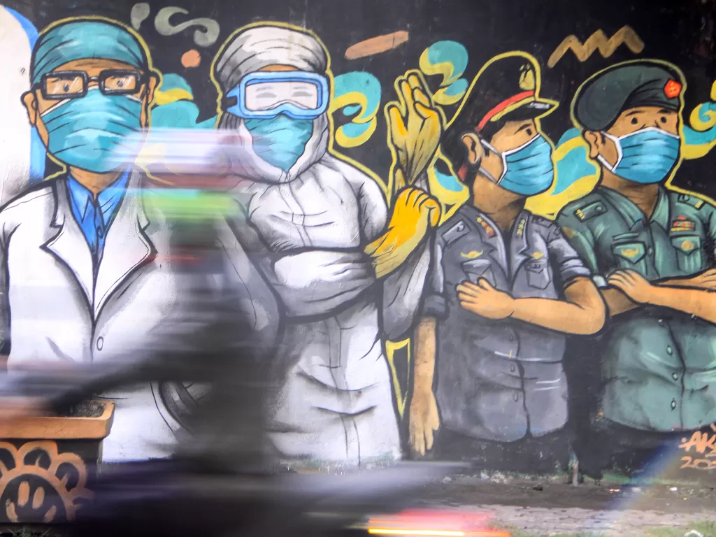 Pengendara melintas di depan mural tentang pandemi corona (Covid-19) di Kawasan Bangil, Pasuruan, Sidoarjo, Jawa Timur. (ANTARA/Umarul Faruq)