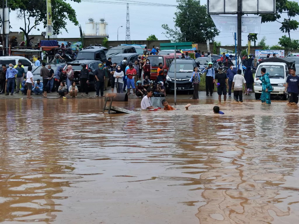Sejumlah warga berdiri menunggu banjir surut di Kotasari, Grogol, Cilegon, Banten, Senin (4/5/2020). (ANTARA/Asep Fathulrahman)