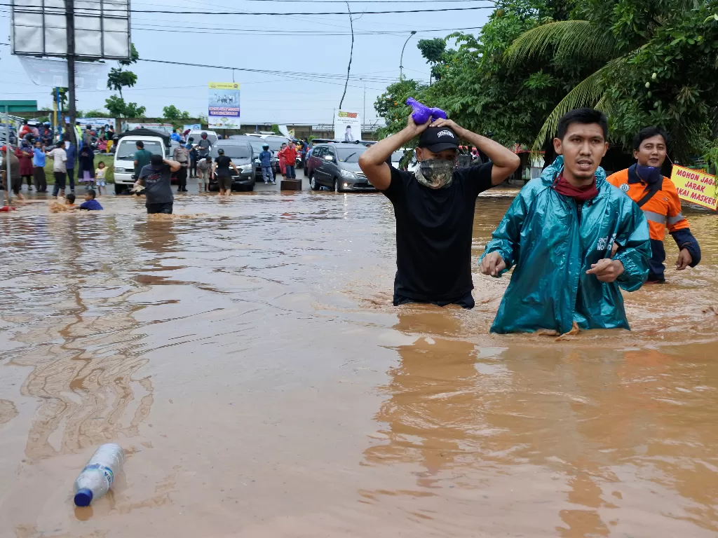 Warga berjalan menerobos banjir di Kotasari, Grogol, Cilegon, Banten, Senin (4/5/2020). (ANTARA/Asep Fathulrahman)