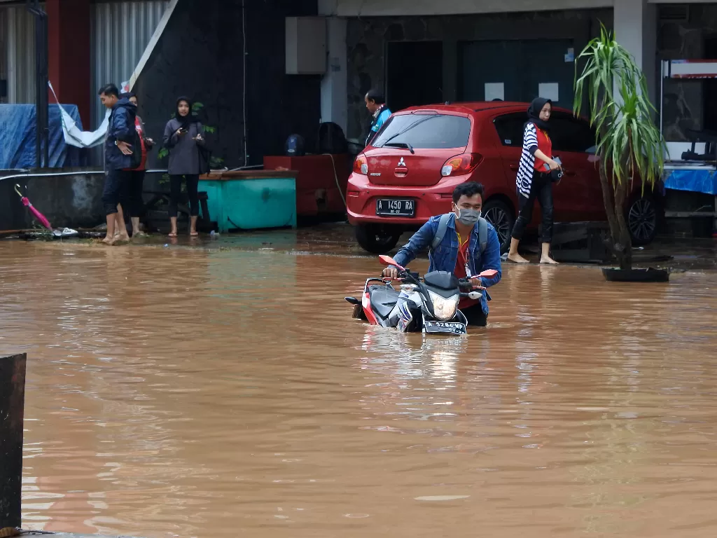 Warga mendorong sepeda motor yang mogok terendam banjir di Kotasari, Grogol, Cilegon, Banten, Senin (4/5/2020). (ANTARA/Asep Fathurahman)